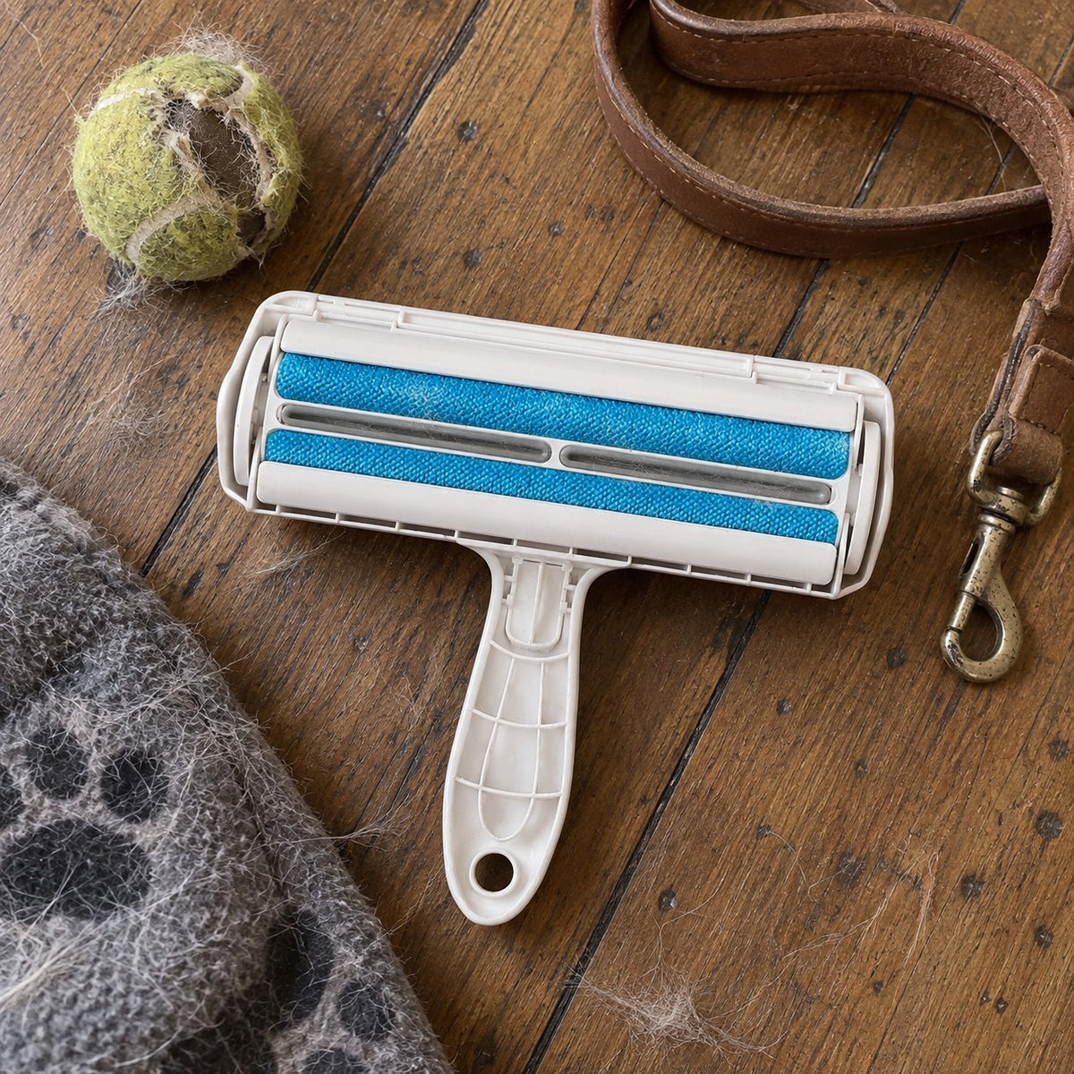 Reusable pet hair roller with two blue fabric brushes on timber floorboards